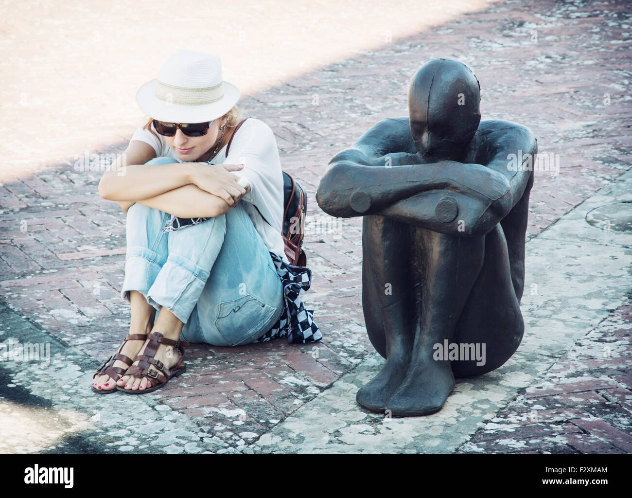 Junge Frau sitzt und die Pose der Eisen Statue imitiert. Forte di Belvedere, Florenz, Italien. Stockfoto
