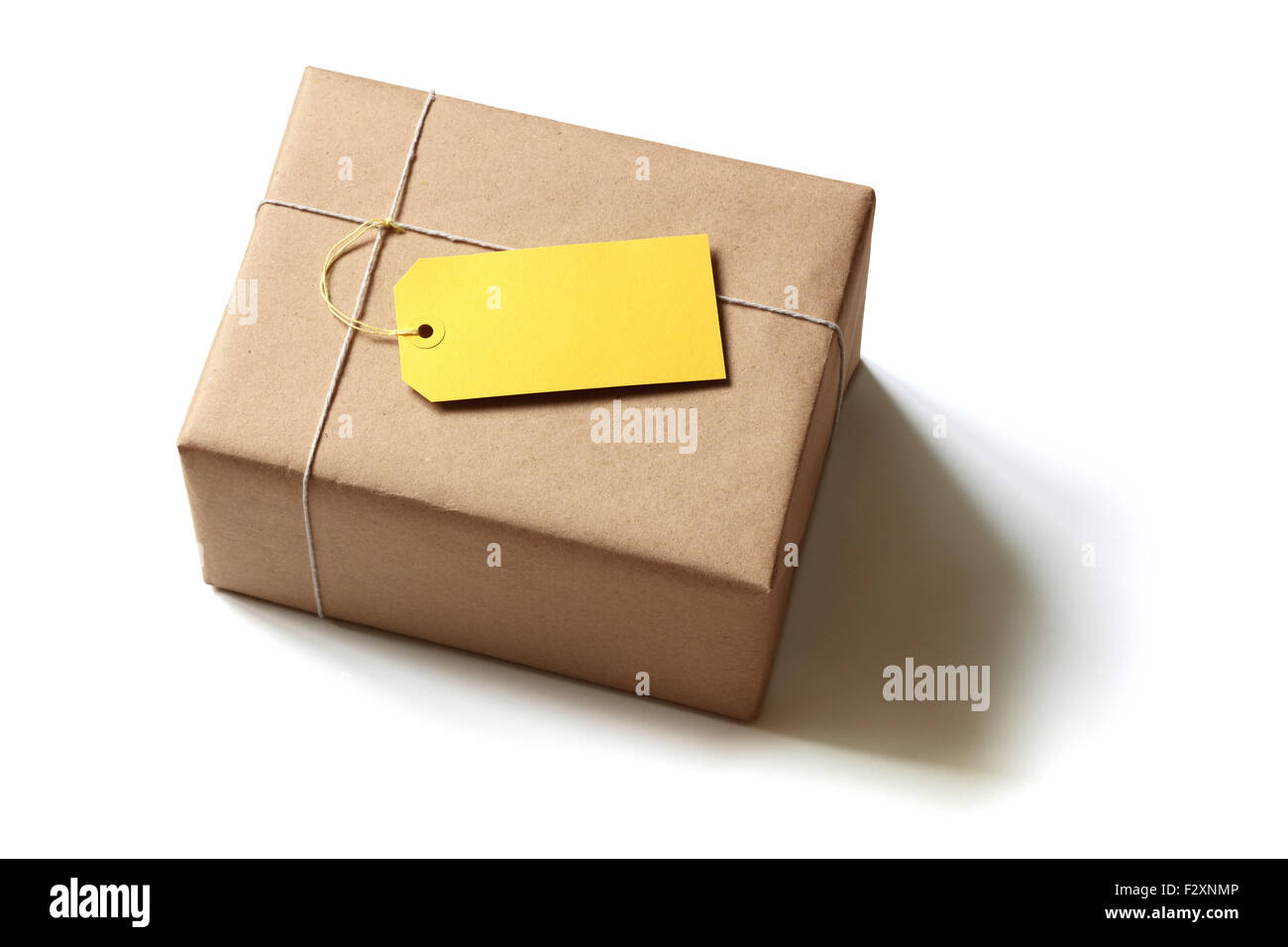Geschenk-Paket verpackt in braunem Recyclingpapier mit leeren gelben Aufkleber isoliert auf weiss Stockfoto