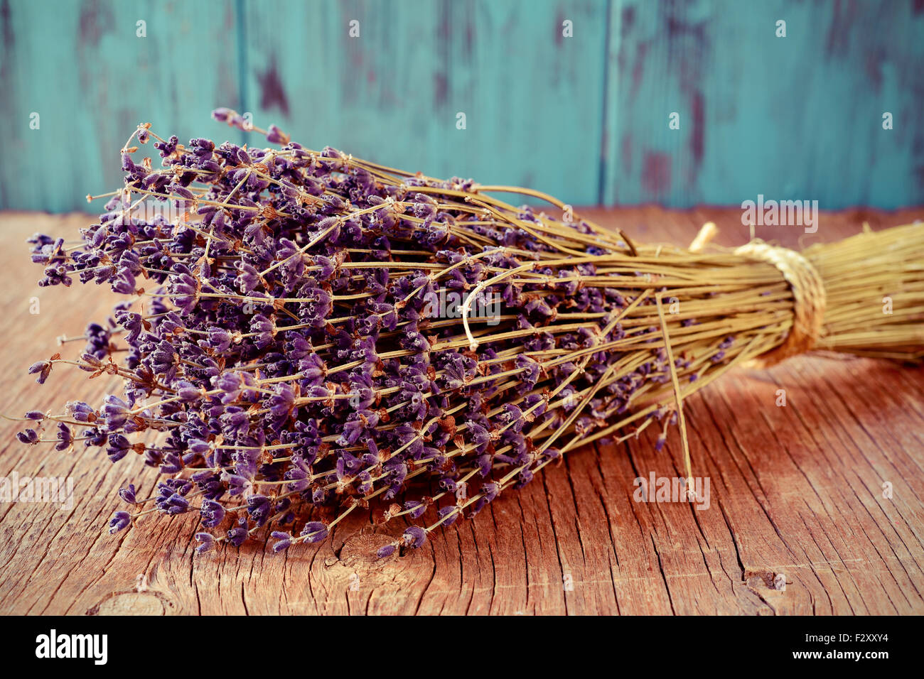 Nahaufnahme von einer Handvoll Lavendelblüten gebunden mit einer Schnur an einen rustikalen hölzernen Hintergrund Stockfoto