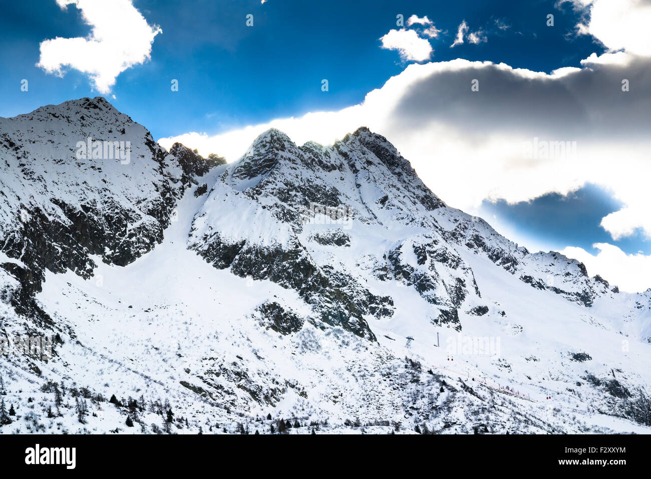 Blick auf die Spitze eines Berges bedeckt mit Schnee und die Sonne in den Wolken versteckt. Stockfoto
