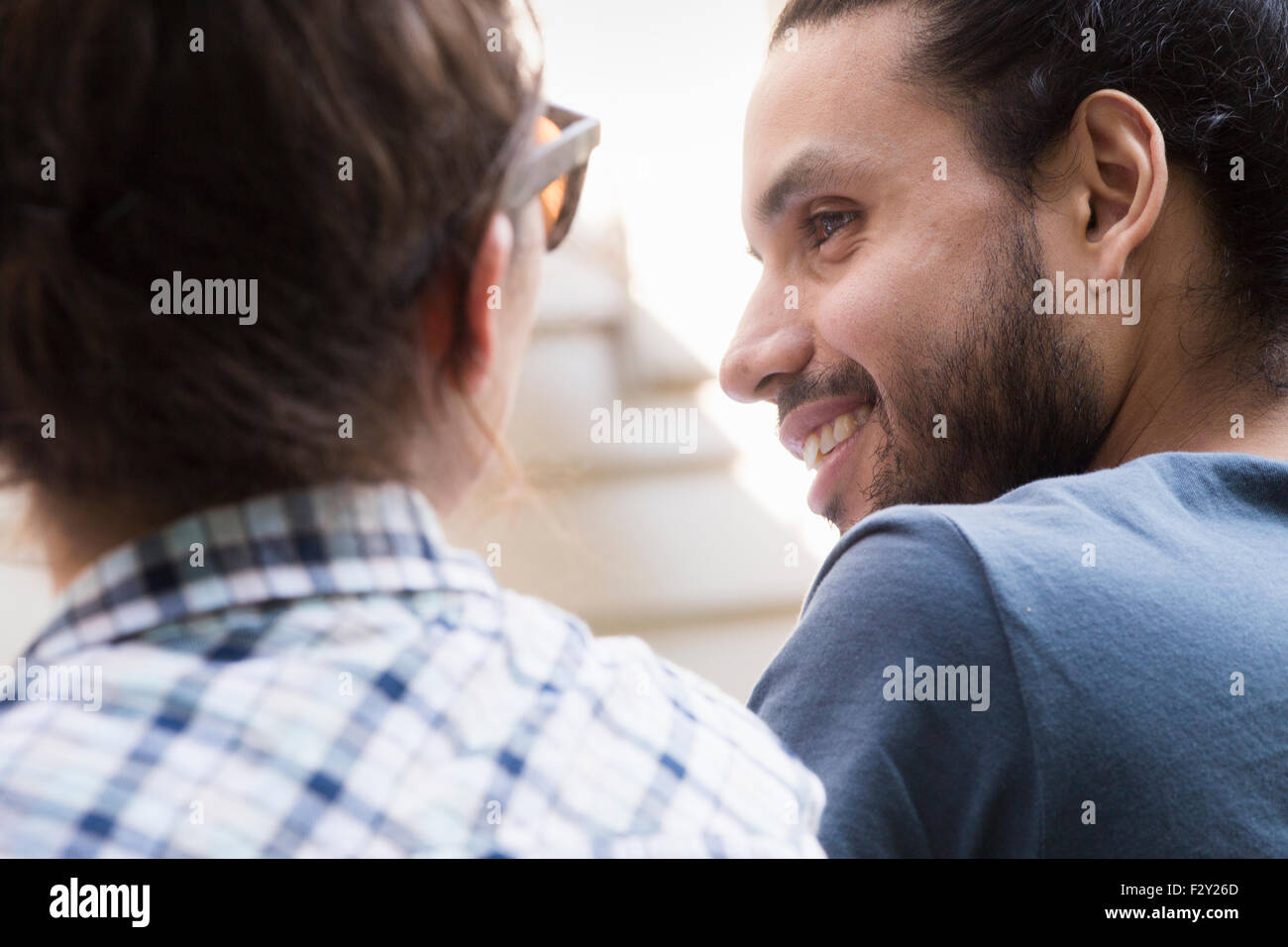 Ein junger Mann und eine Frau sitzen nebeneinander, lächelnd und reden. Stockfoto