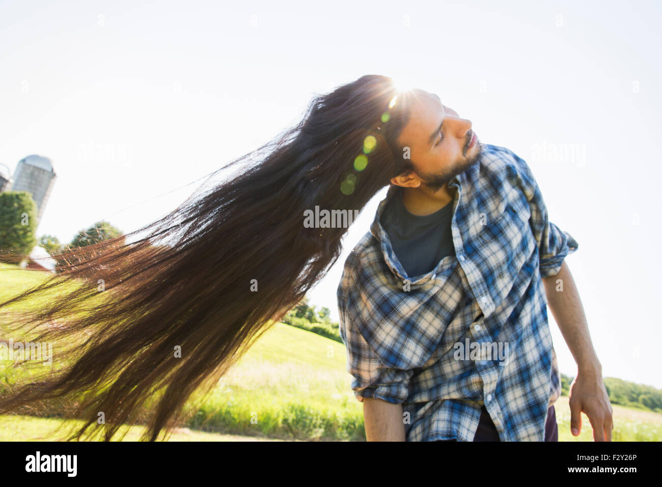 Ein junger Mann im Stich sein sehr langes dunklen Haares und schüttelte den Kopf, um es draußen an der frischen Luft Ventilator. Stockfoto