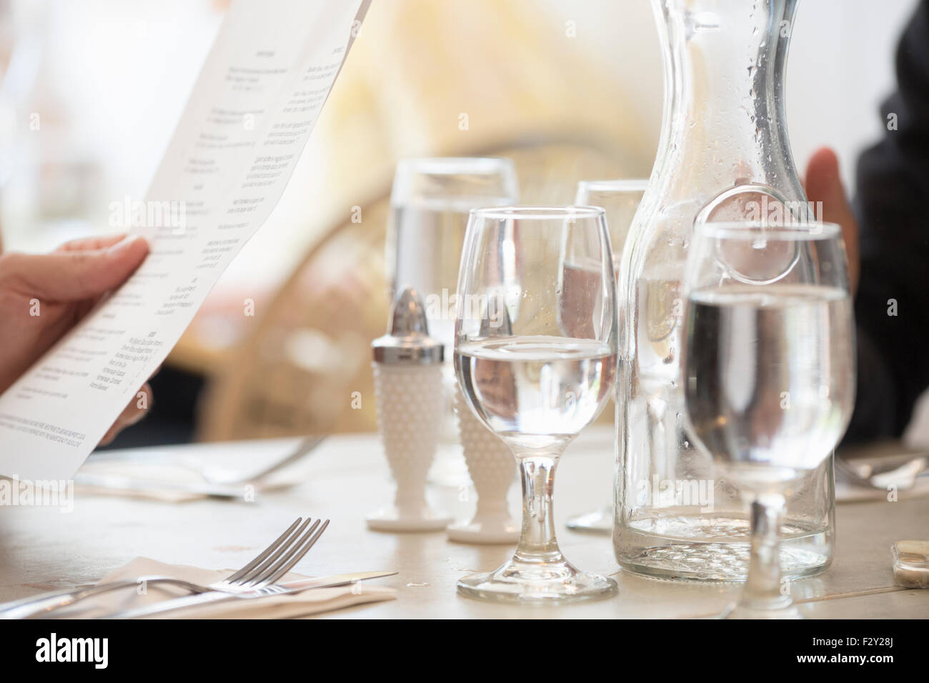 Nahaufnahme von Wein und Wassergläser und Gedecke an einem Tisch in einem Restaurant. Eine Person, die Hand, die das Menü. Stockfoto