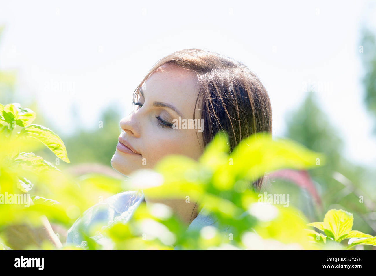 Junge Frau im freien umgeben von grünen Pflanzen. Stockfoto