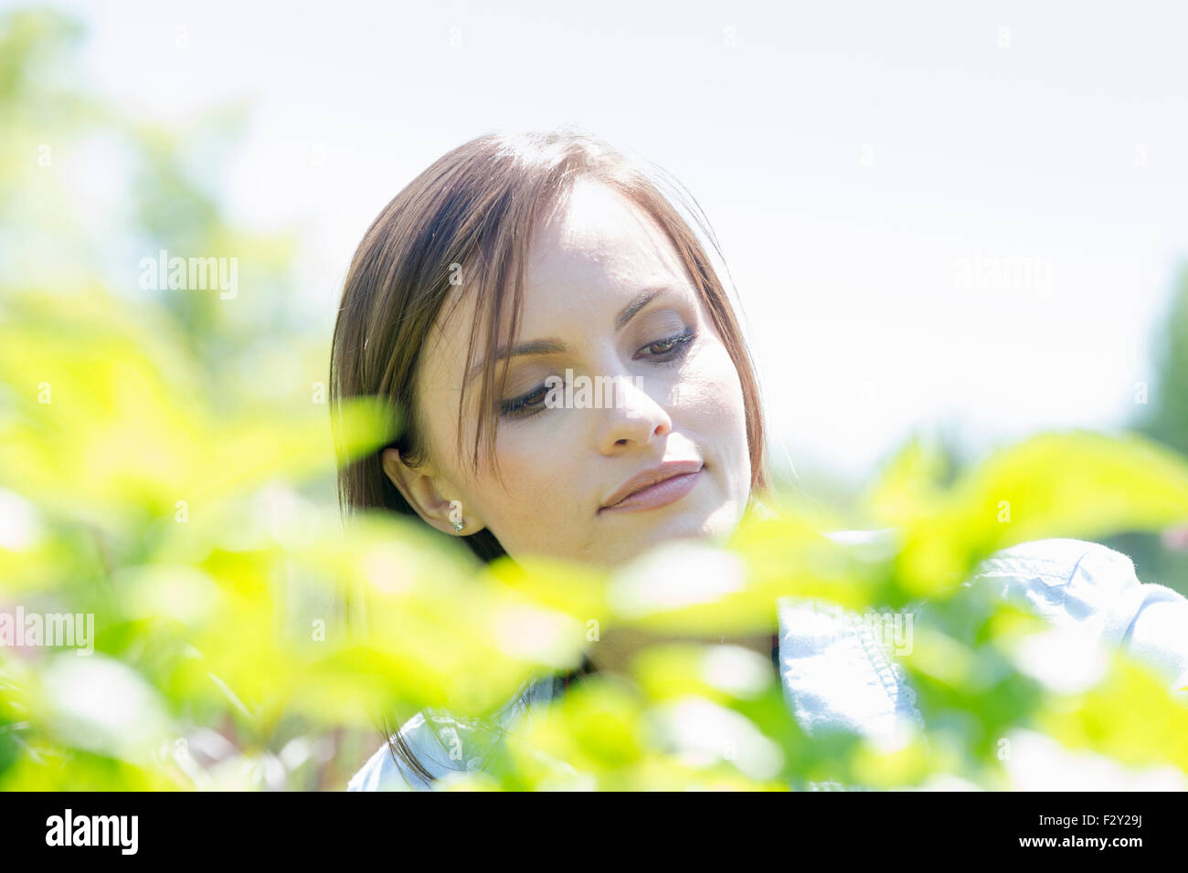 Junge Frau im freien umgeben von grünen Pflanzen. Stockfoto