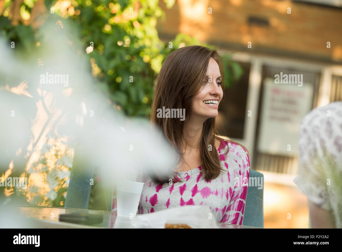 Eine Frau sitzt an einem Tisch im Garten. Stockfoto