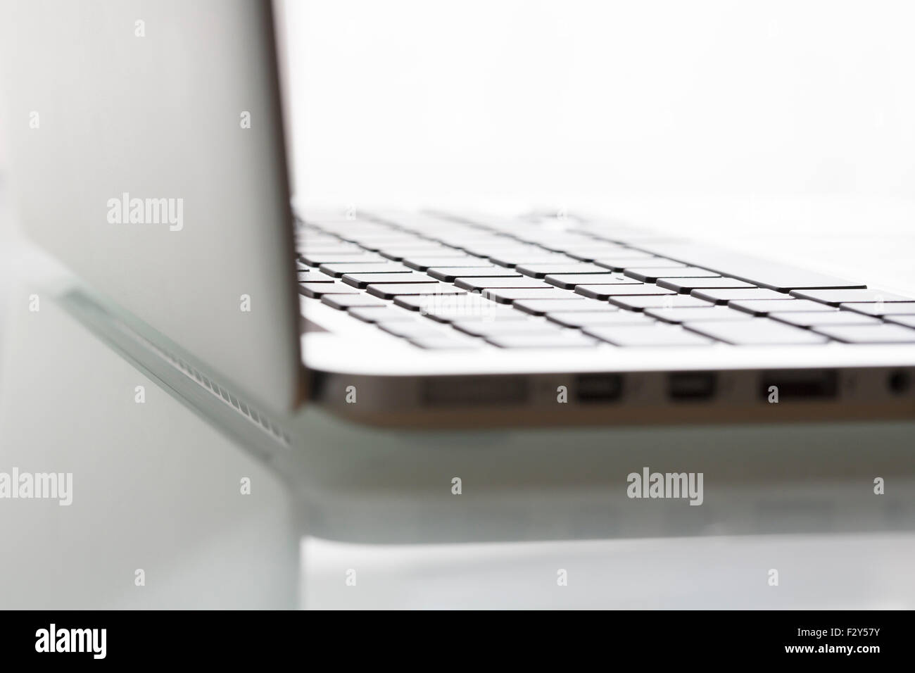 Laptop auf modernen Glastisch im Amt. Tastatur im Fokus Stockfoto