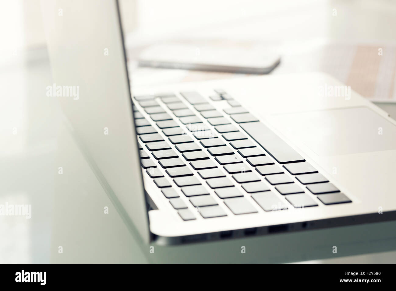 Laptop auf modernen Glastisch im Amt. Tastatur im Fokus Stockfoto