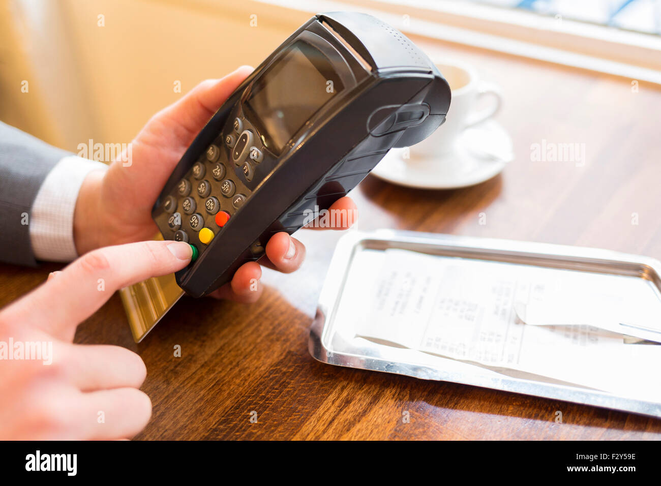 Hand des Mannes mit Kreditkarte Swipe über Terminal zu verkaufen, im Restaurant. Code-Tastatur Stockfoto