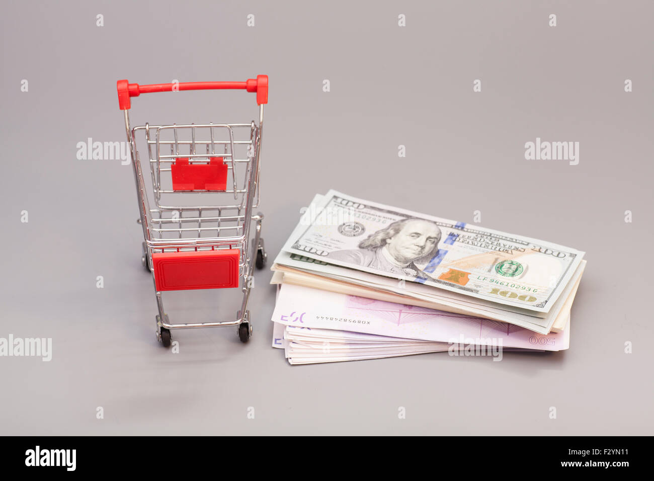 Warenkorb mit Geld (Dollar, Euro) auf grauem Hintergrund isoliert Stockfoto