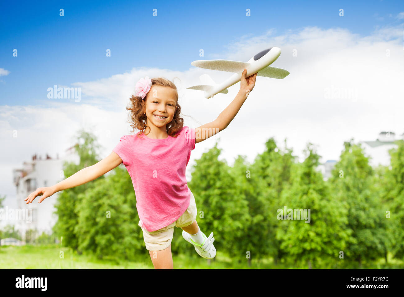 Mädchen hält Flugzeug Spielzeug allein mit einem Bein Stockfoto