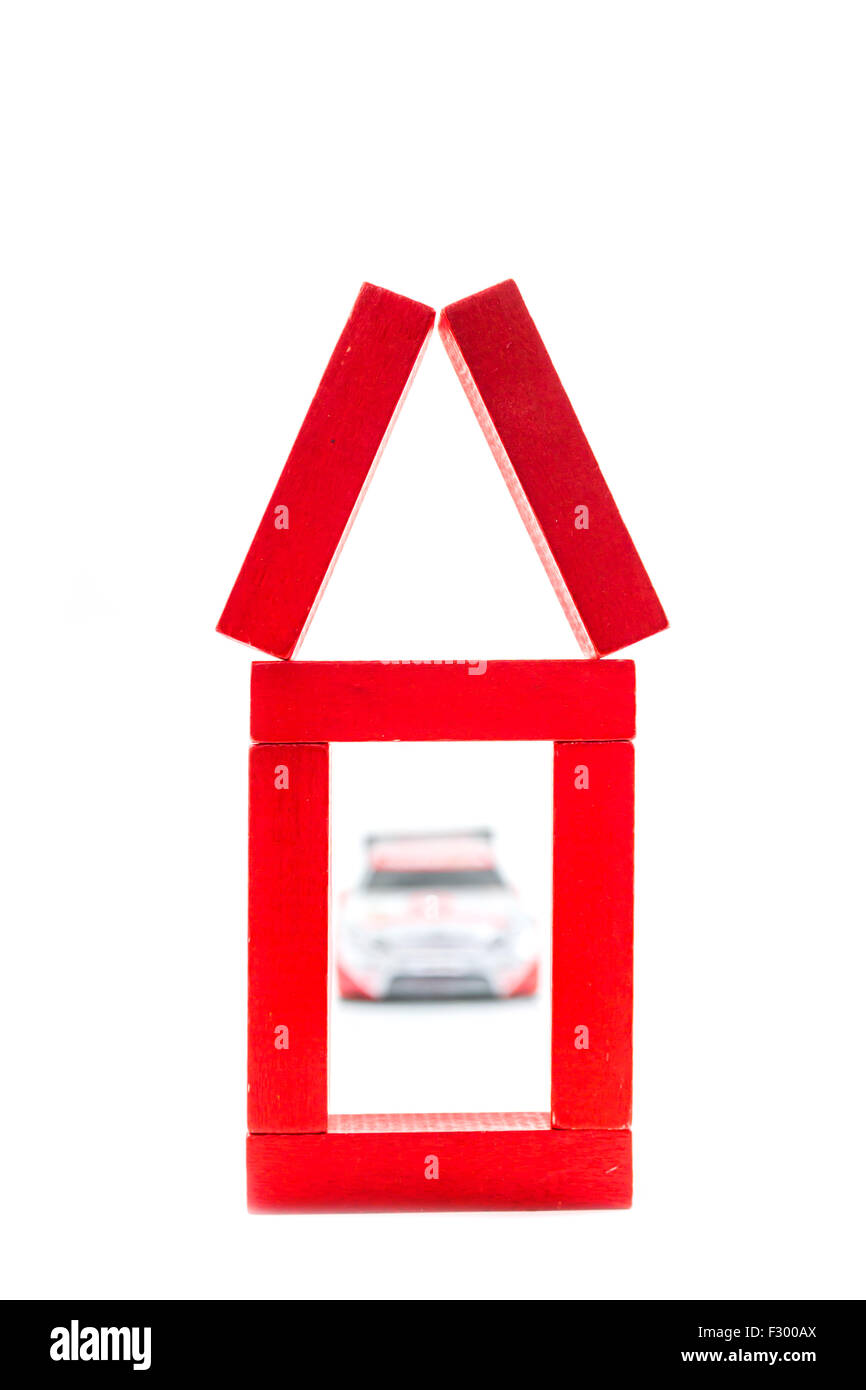 Rote Haus aus Holzspielzeug mit Auto auf weißem Hintergrund Stockfoto
