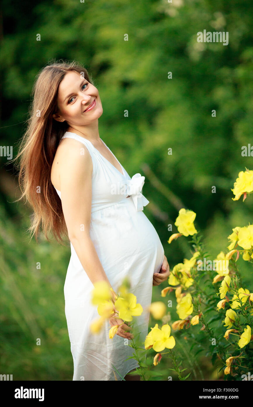 Schwangere Frau posiert in einem grünen Garten Stockfoto