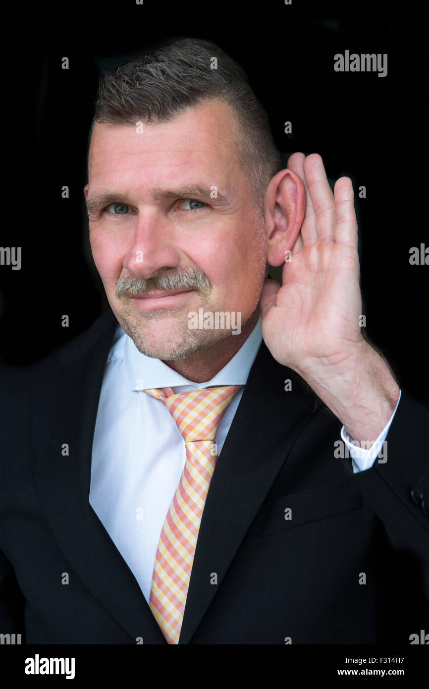 Geschäftsmann mit Hand an sein Ohr hören möchten Stockfoto