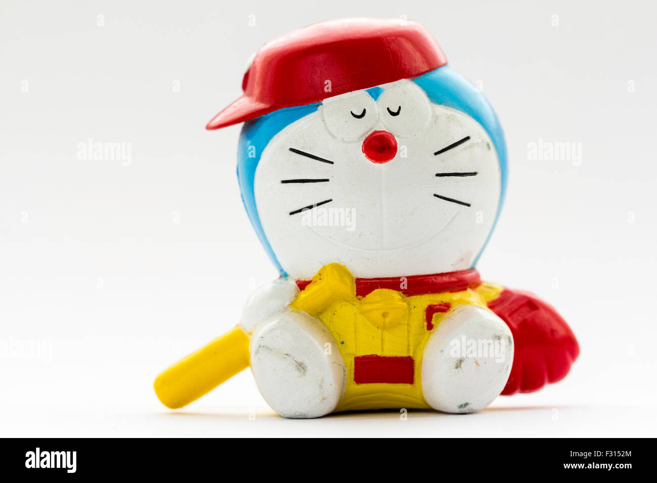 Doraemon, Japanisch berühmten Cartoon anime Charakter. Kunststoff Modell von ihm mit Baseballschläger sitzen und tragen Baseball Hut gegen weißen Hintergrund. Stockfoto