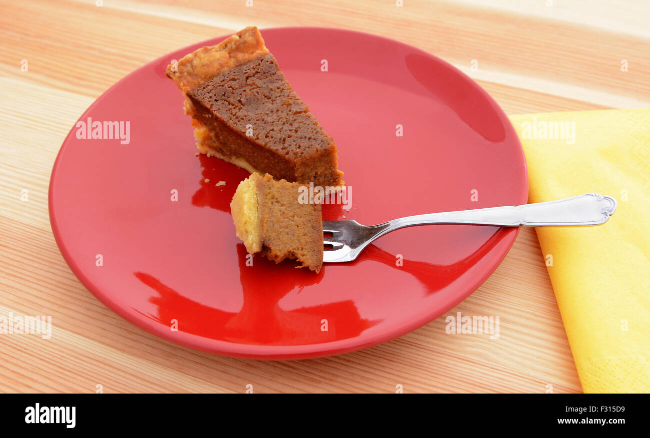 Bissen von leckeren Kürbiskuchen auf eine silberne Gabel auf einer roten Platte Stockfoto