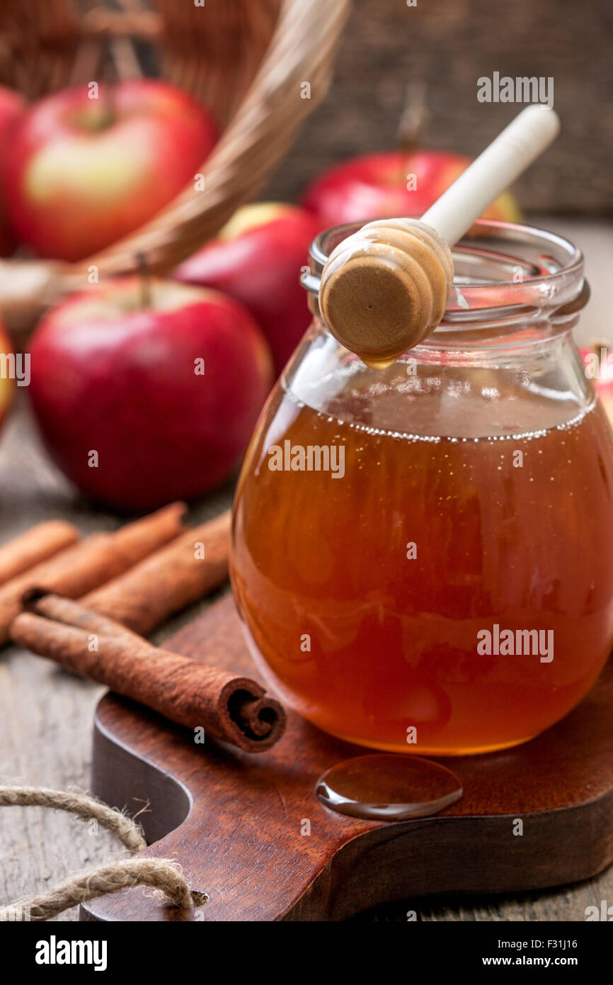 Honig-Löffel, Glas Honig, Äpfeln und Zimt auf einem hölzernen Hintergrund Stockfoto
