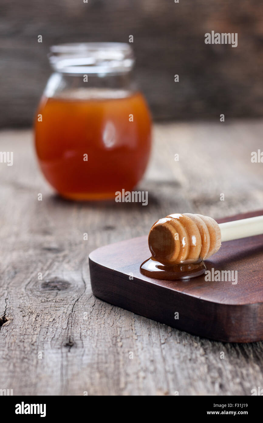 Honig-Löffel an Bord,, Bank mit Honig auf den alten hölzernen Hintergrund Stockfoto