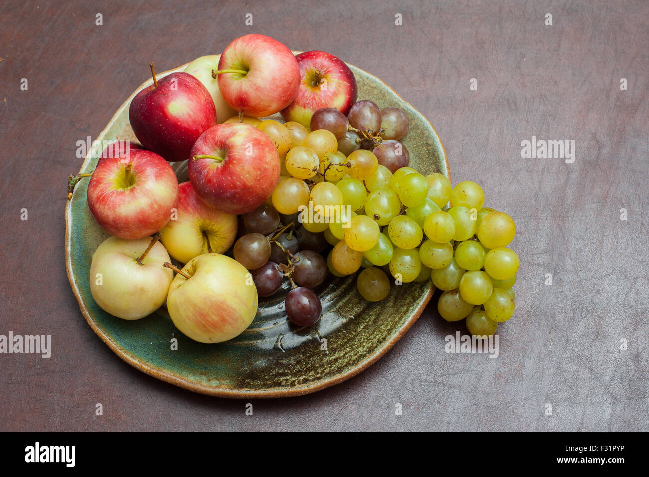 Platte mit frischen herbstlichen Früchte, Äpfel und Trauben auf braunen Tisch Stockfoto