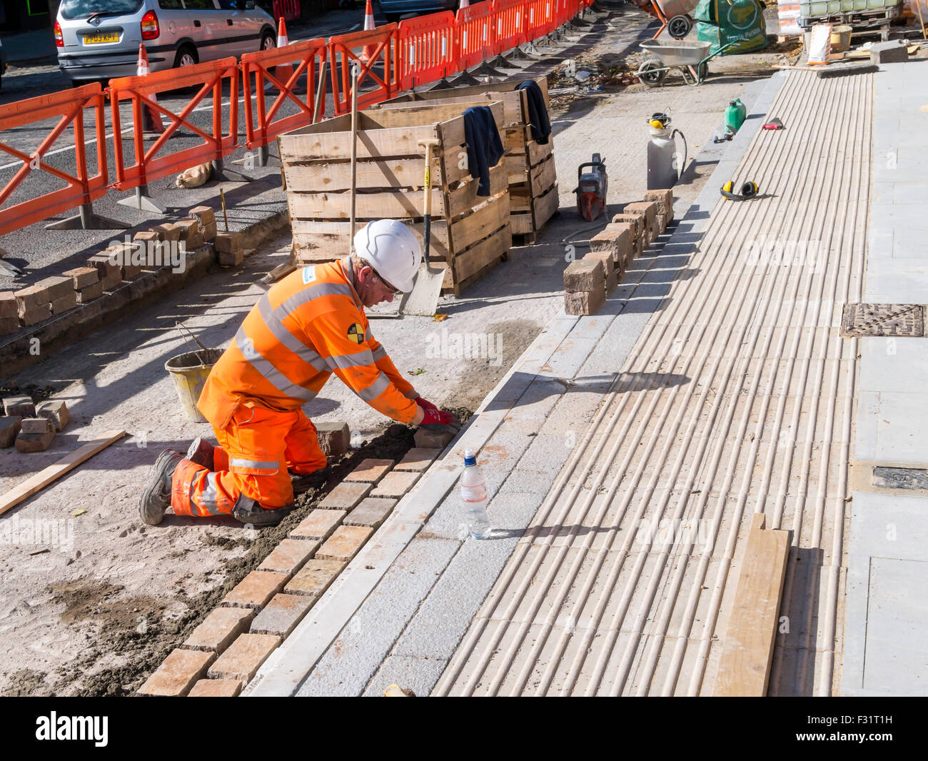 Ein Arbeiter, die Verlegung einer neuen Granit Block Straßendecke an einem neuen Standort der Bushaltestelle North Yorkshire England Stockfoto
