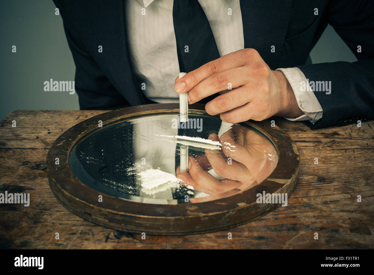 Junger Geschäftsmann ist Schnauben Kokain mit einem zusammengerollten Geldschein Stockfoto