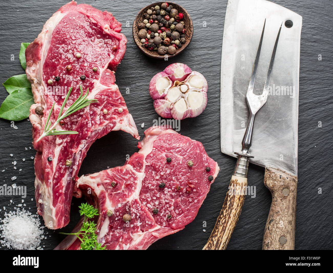 Rohes Rindfleisch Steaks mit Gewürzen auf schwarze Schneidebrett. Stockfoto
