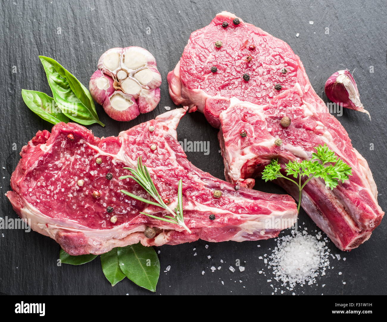 Rohes Rindfleisch Steaks mit Gewürzen auf schwarze Schneidebrett. Stockfoto
