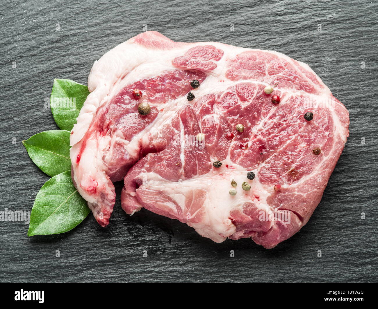 Rohes Rindfleisch Steaks mit Gewürzen auf dem schwarzen Schneidebrett. Stockfoto