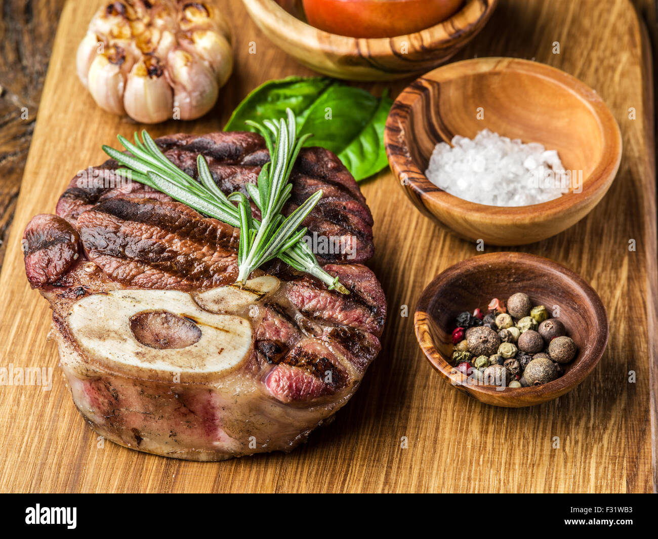 Rindersteaks mit Gewürzen auf einem Holztablett. Stockfoto