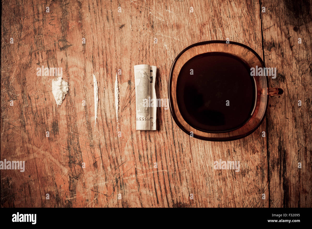 Eine Tasse Kaffee mit Kokain und einen zusammengerollten Geldschein daneben Stockfoto