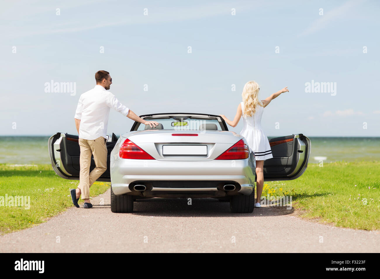 glücklicher Mann und Frau in der Nähe von Cabrio Auto am Meer Stockfoto