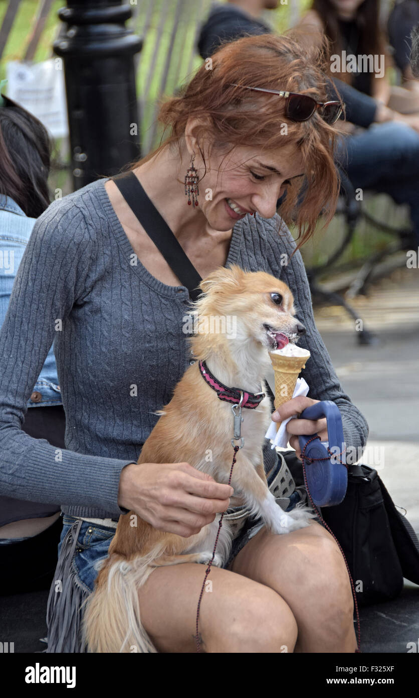 Eine attraktive Frau teilt ihr Eis mit ihrem Hund im Washington Square Park in New York City. Stockfoto