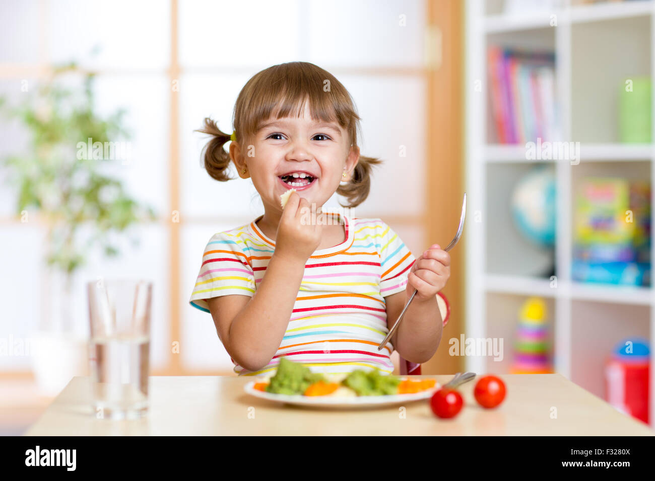 Kind Mädchen essen gesundes Gemüse Stockfoto