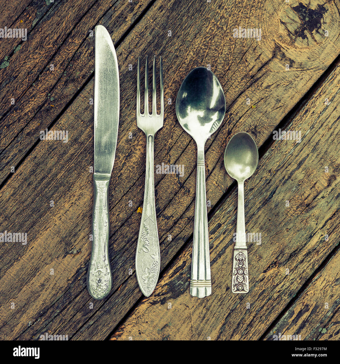 Satz von Vintage besteck Küchengeräte, Messer, Gabel, und zwei Löffel auf Holz Hintergrund. querbearbeitung Effekt hinzugefügt Stockfoto