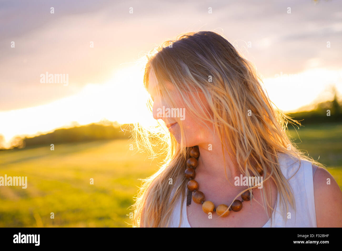 Eine starke Hintergrundbeleuchtung Porträt einer Frau (Alter 25-30) in einem Feld an einem Sommerabend Stockfoto