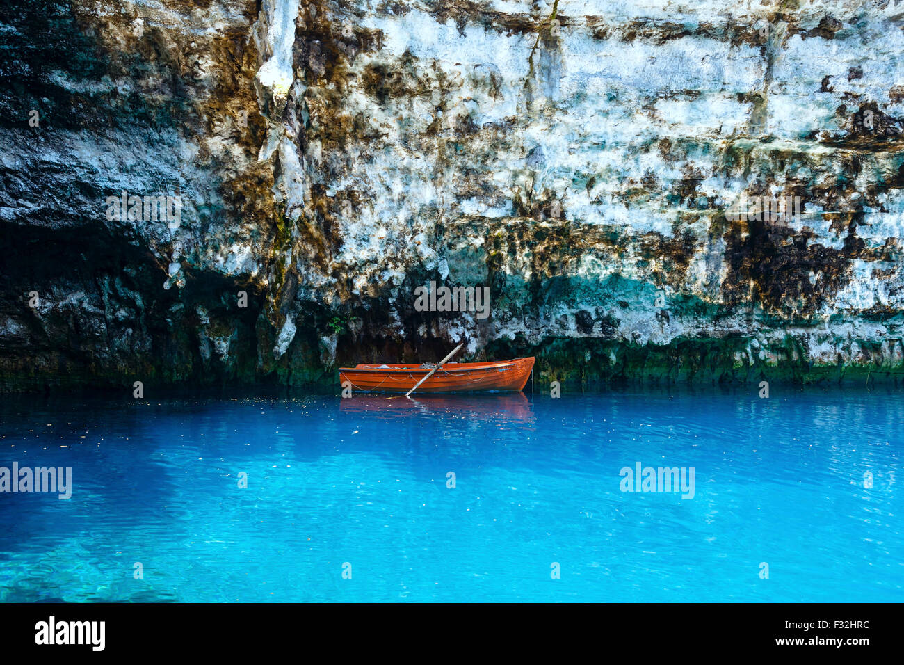 Holzboot in der Nähe von steilen Felsen auf der Oberfläche des unterirdischen Sees (Melissani, Kefalonia, Griechenland). Stockfoto