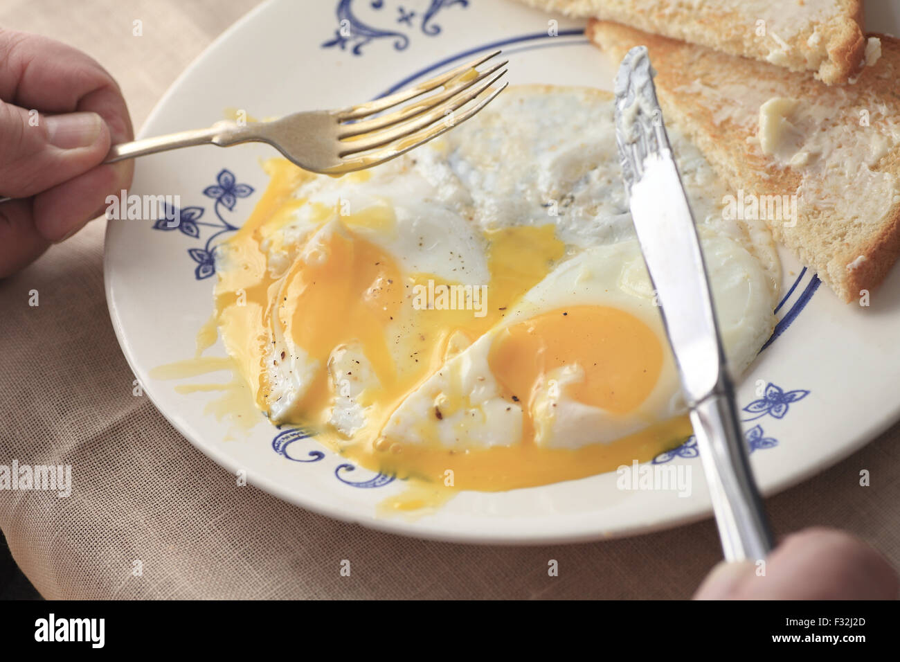 Ein Mann hält ein Messer und Gabel in der Vorbereitung für sein Frühstück Essen. Stockfoto