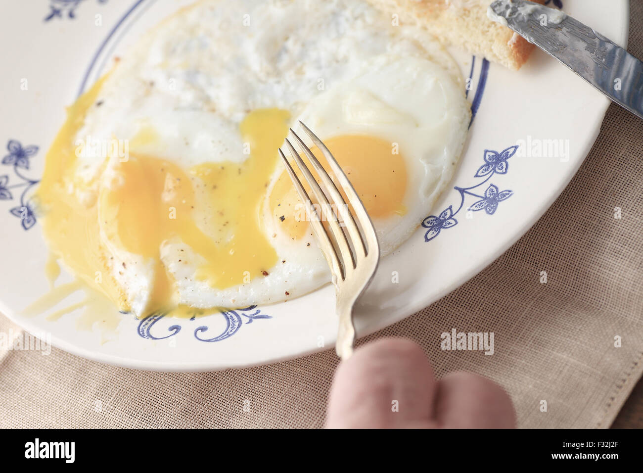 Ein Mann ist bereit, seine Mahlzeit am Morgen der laufende Spiegeleier mit Toast mit Butter zu essen. Stockfoto