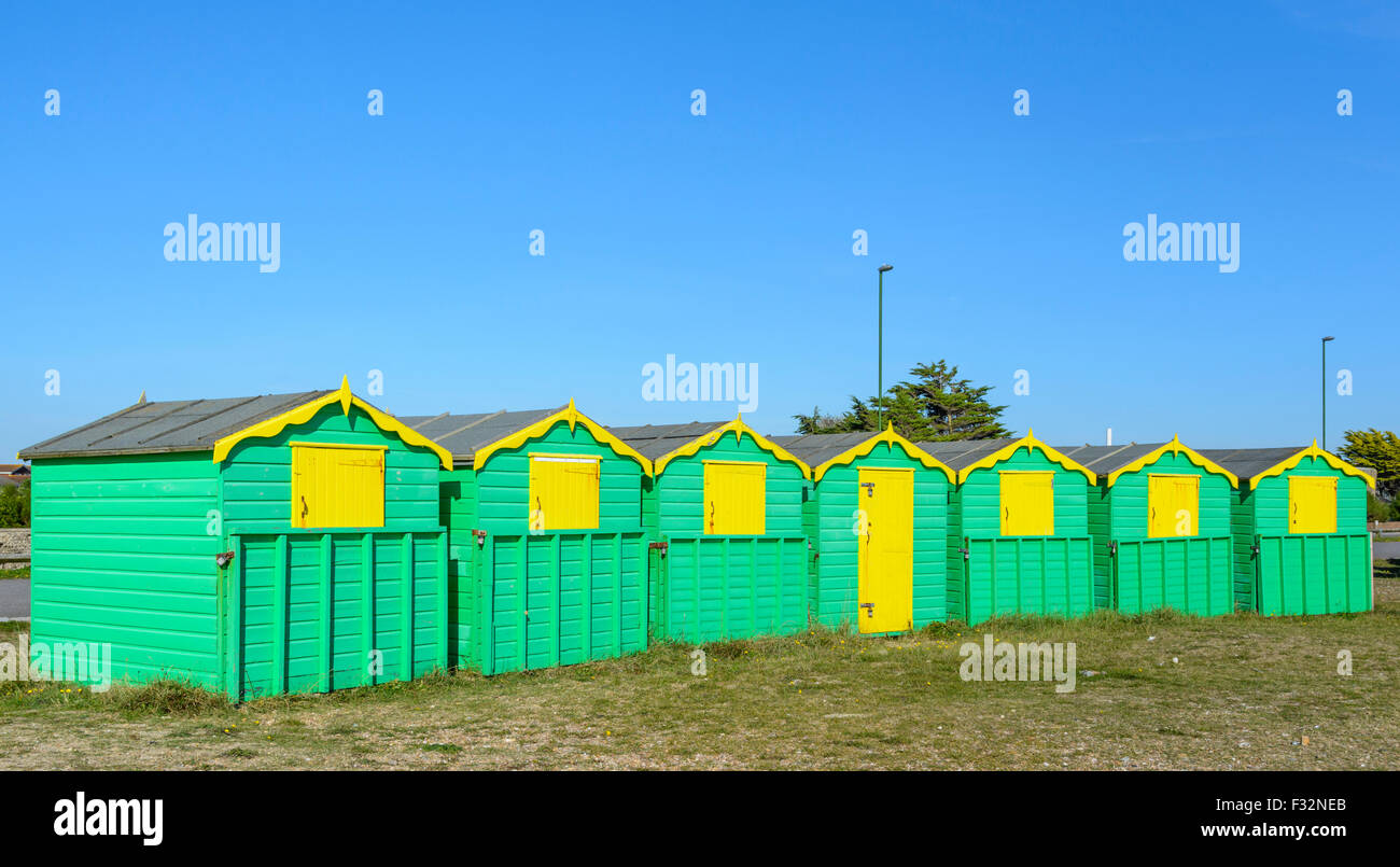 Badehäuschen UK. Grüne und gelbe Strand Hütten an einem sonnigen Tag mit blauem Himmel in Littlehampton, West Sussex, England, UK. Stockfoto
