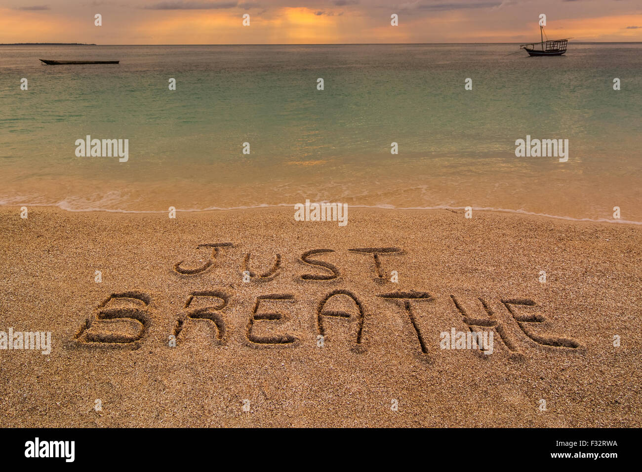 Auf dem Bild einen Strand bei Sonnenuntergang mit den Worten auf dem Sand "einfach atmen Sie". Stockfoto