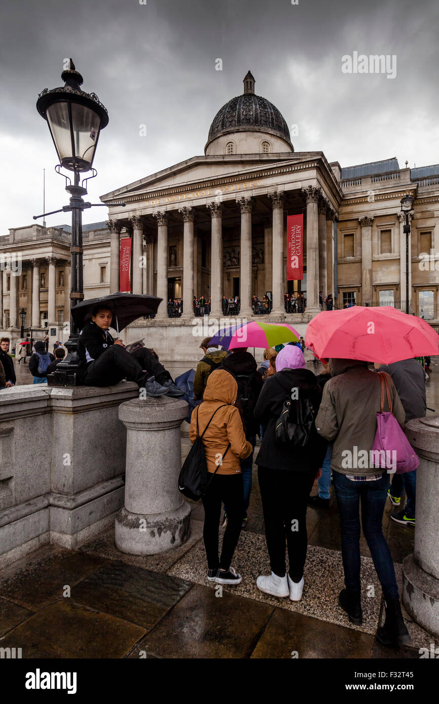 Besuchern stehen außerhalb der Nationalgalerie im Regen, London, UK Stockfoto