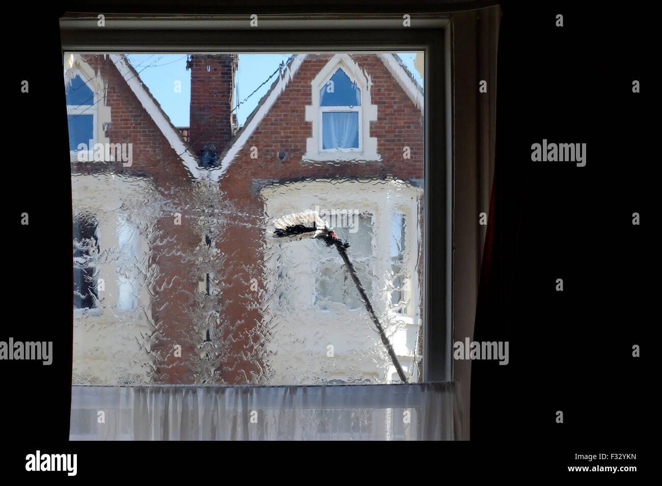 eine Fenster-Reiniger Bürste fegt über die Glasscheibe aus dem Inneren des Raumes gesehen Stockfoto