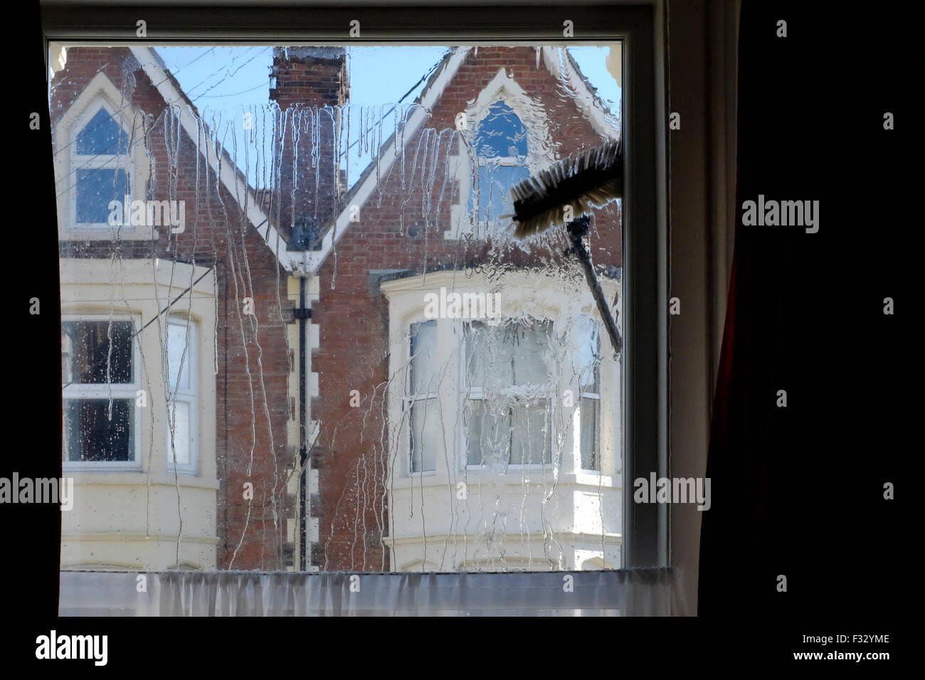 eine Fenster-Reiniger Bürste fegt über die Glasscheibe aus dem Inneren des Raumes gesehen Stockfoto