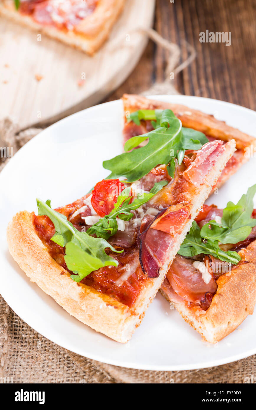 Schinken-Pizza mit Rucola, frischen Tomaten, Knoblauch und Käse Stockfoto