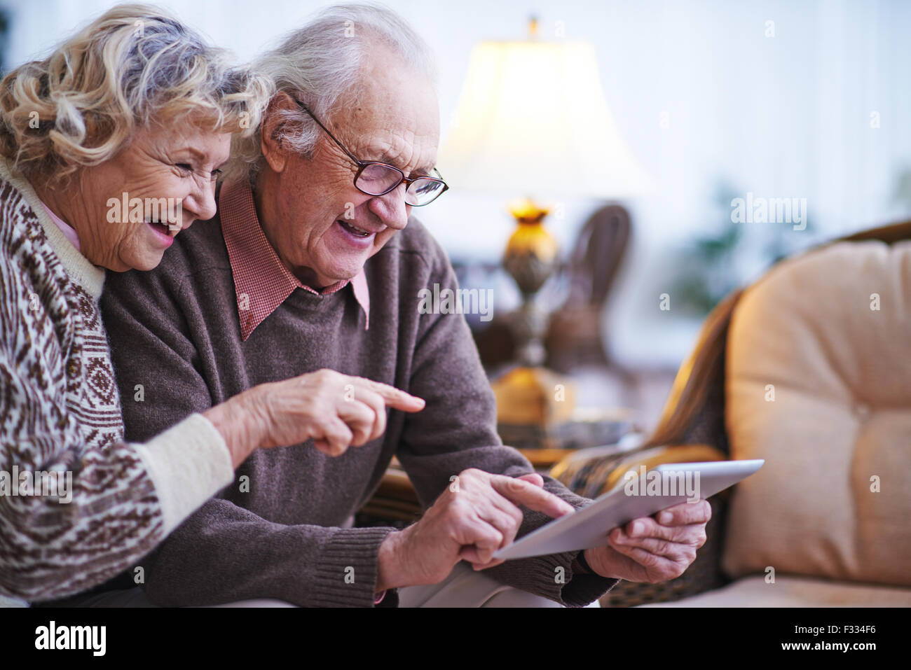 Gerne älteres Paar mit Touchpad zu Hause Stockfoto