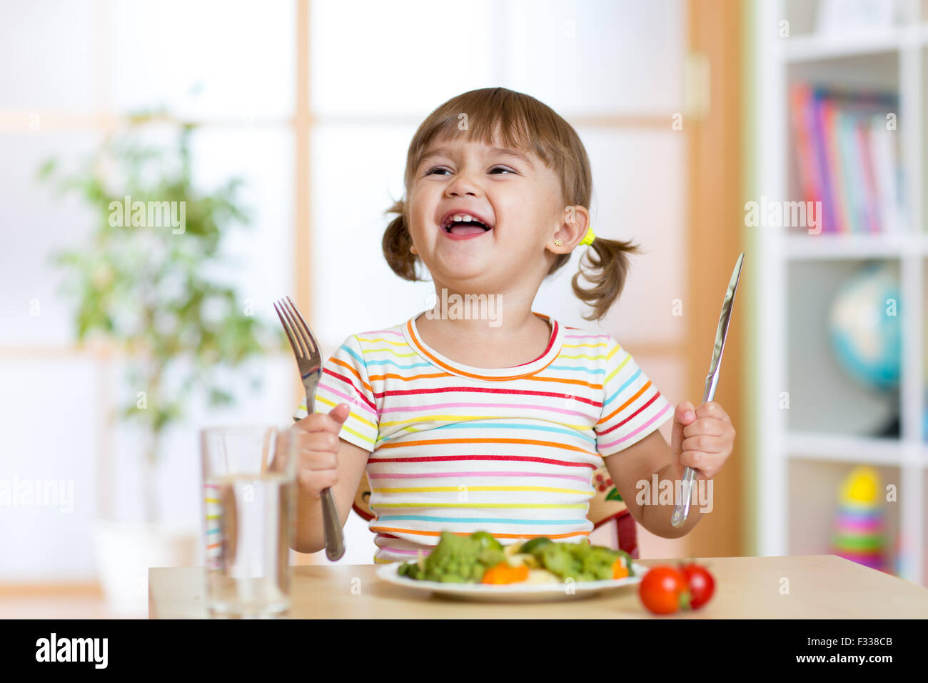 glückliche kleine Mädchen mit gesunden Speisen zum Abendessen Stockfoto