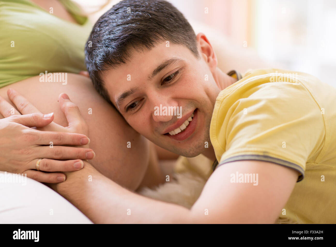 Mann zu seiner Frau Bauch hören Stockfoto