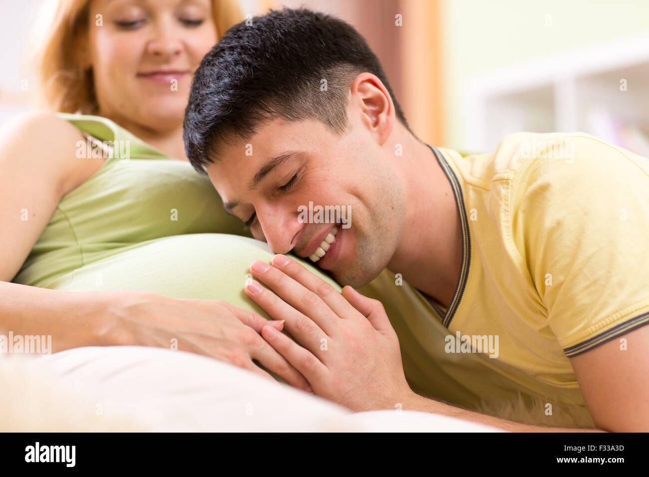 Fröhliche Mann umarmt Bauch seiner schwangeren Frau Stockfoto