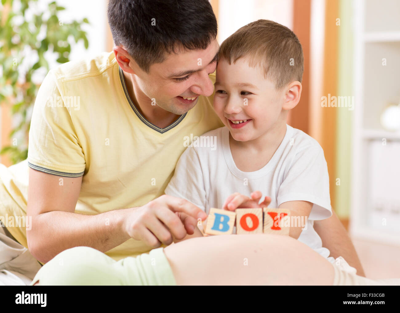 Glückliches Kind junge und sein Vater spielen mit Spielzeug auf Bauch der schwangeren Mutter Stockfoto