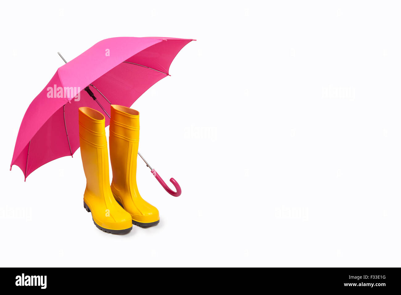 Gelbe Gummistiefel und rosa Regenschirm isoliert Stockfoto